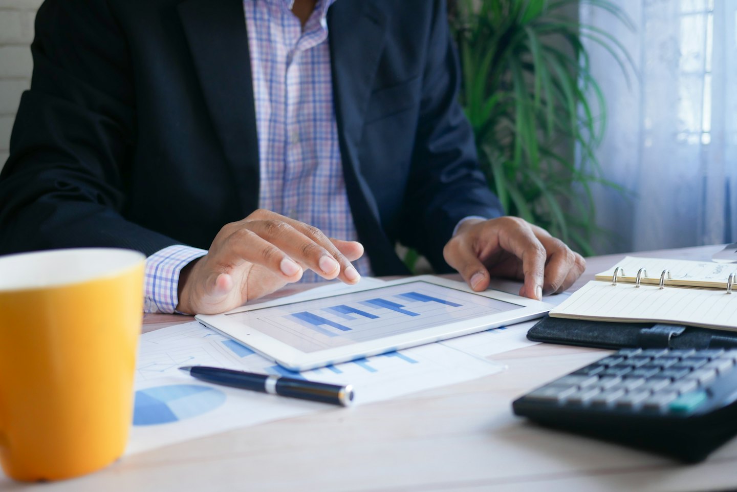 Man studying business data on a tablet at his desk.
